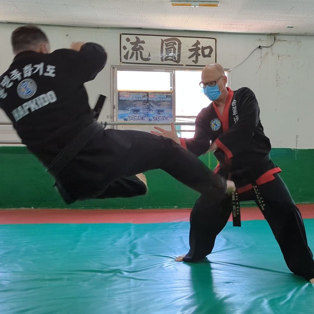 Adult students practice punches together during an evening class.